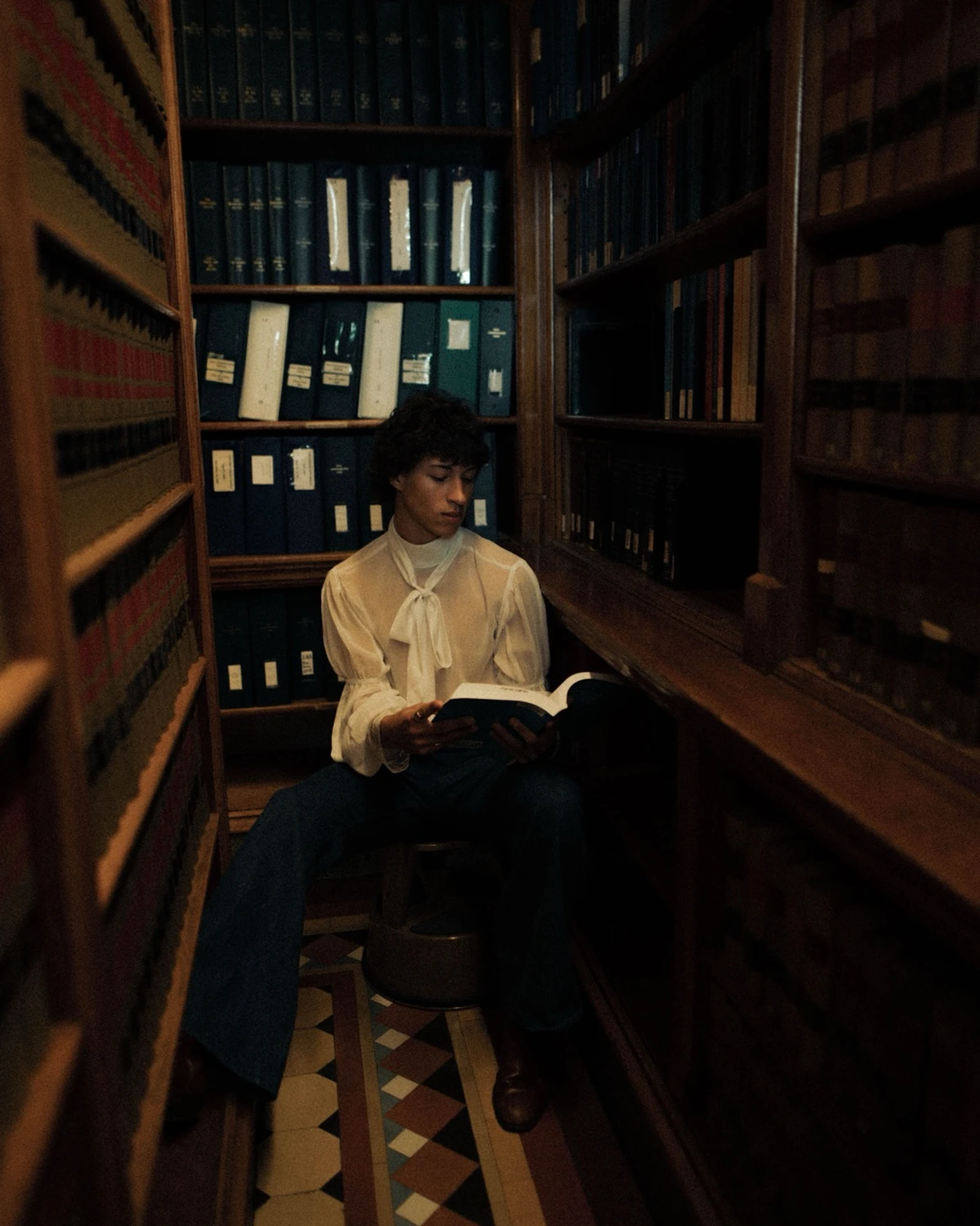 Leerling leest in een donkere bibliotheek als beeld voor eindexamen- en toetsvoorbereiding.